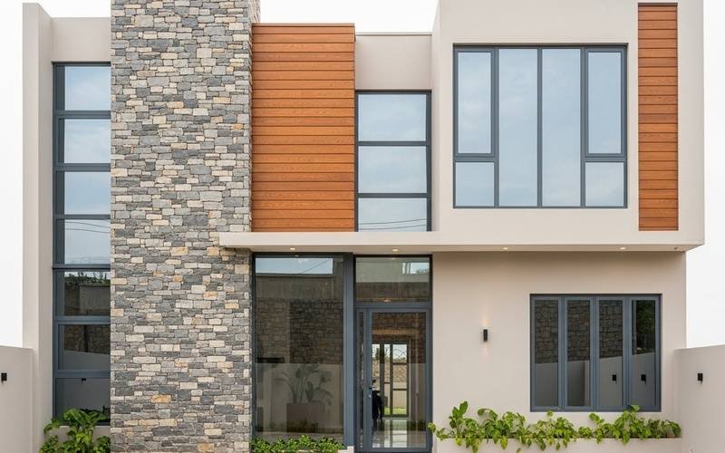 Best 3 Marla Front Elevation Design in Pakistan featuring a modern double-story home with stone cladding, wooden panels, and wide glass windows.