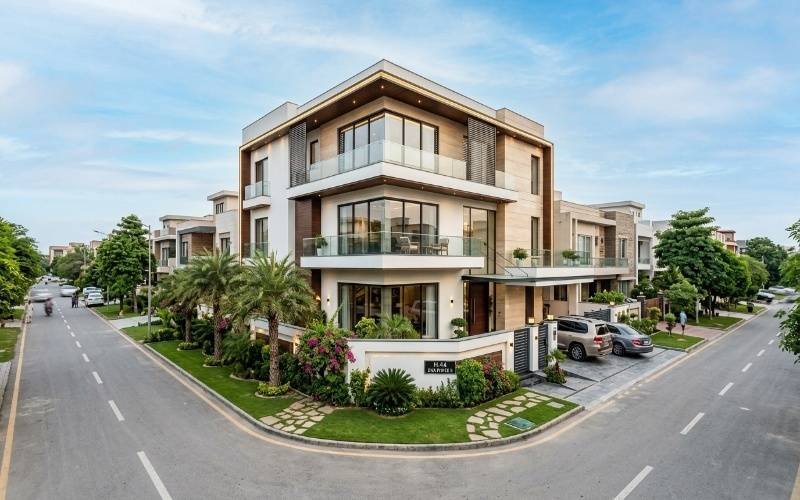 Modern luxury corner home with stylish balconies, large glass windows, landscaped outdoor area, and elegant exterior design showing Corner Plot House Design Plans for a Luxury Look.
